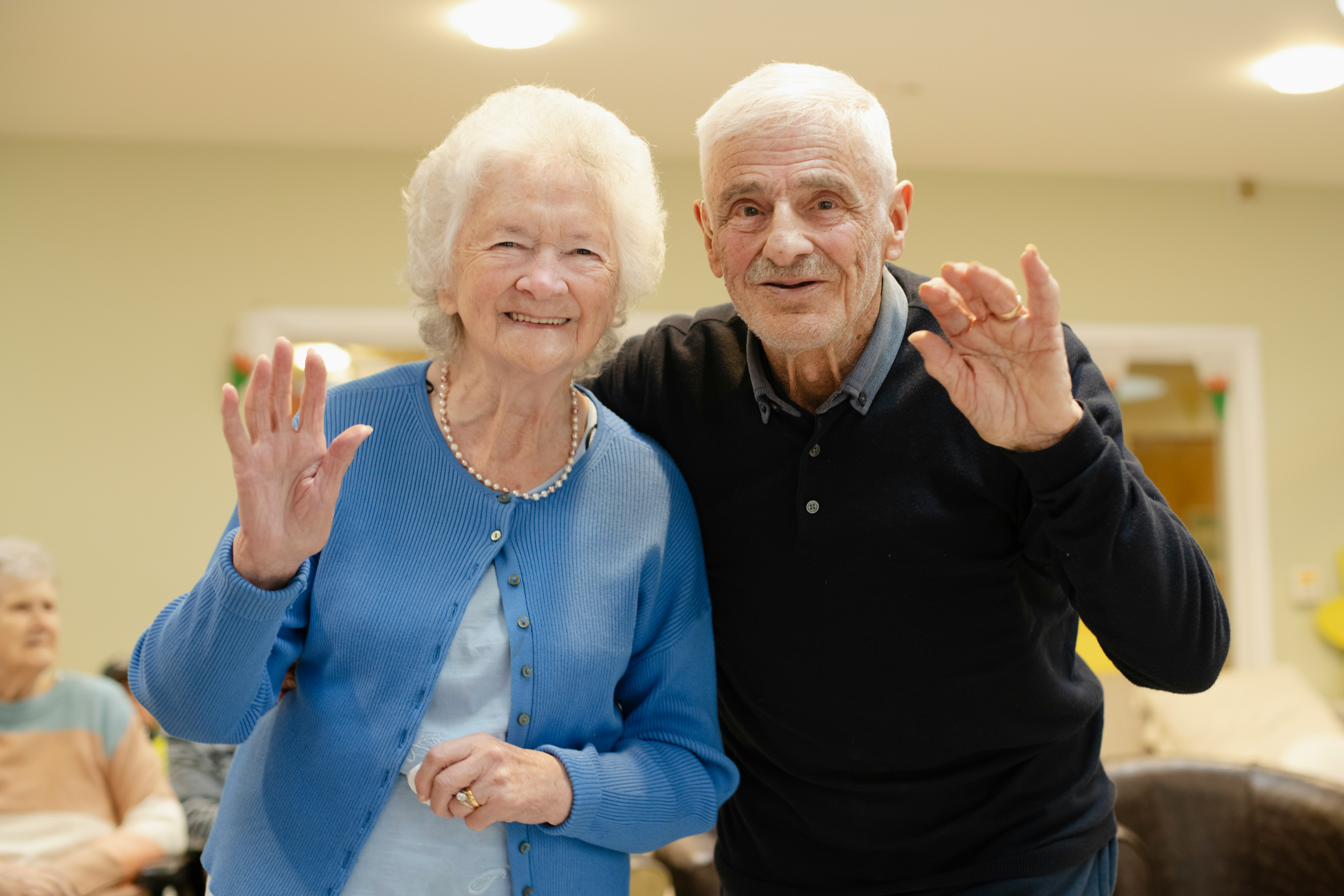 An older couple smiling and waving together